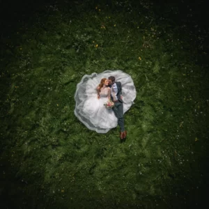 brudepar ligger på gress mens drone tar et bryllupsbildebilde